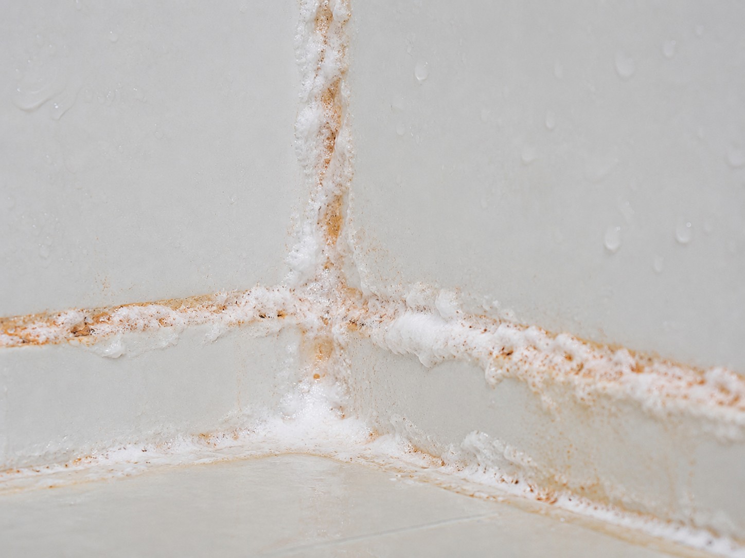 Baking soda and vinegar paste applied to orange stained grout lines