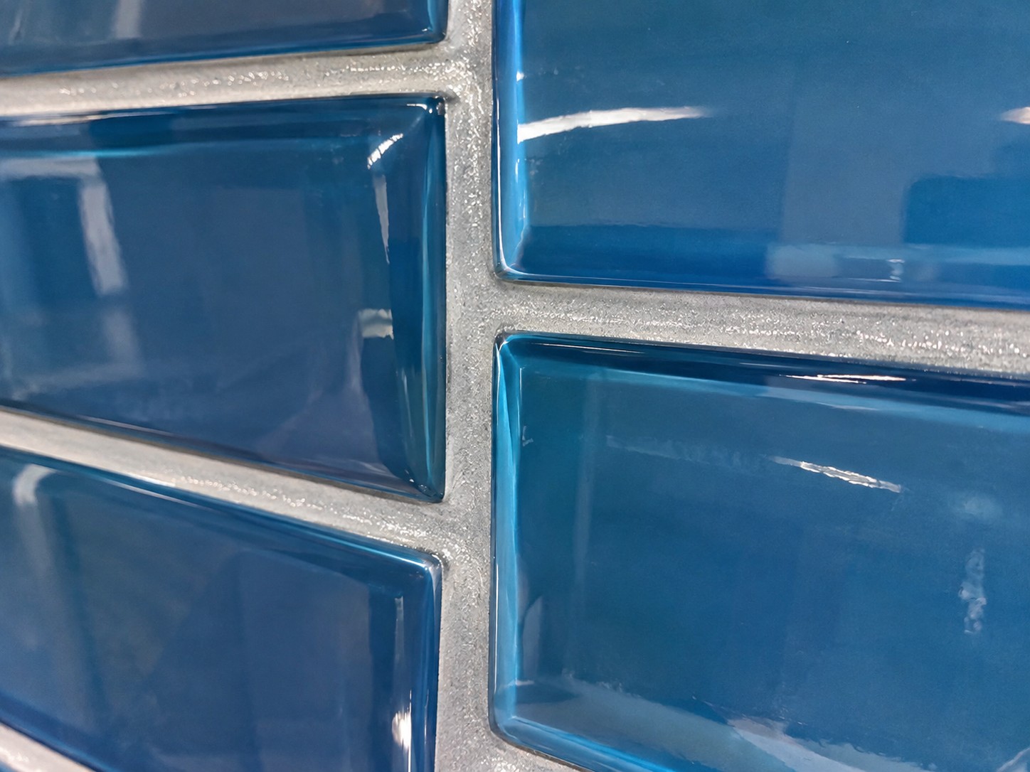 close-up of epoxy grout for glass tile between glossy blue glass subway tiles